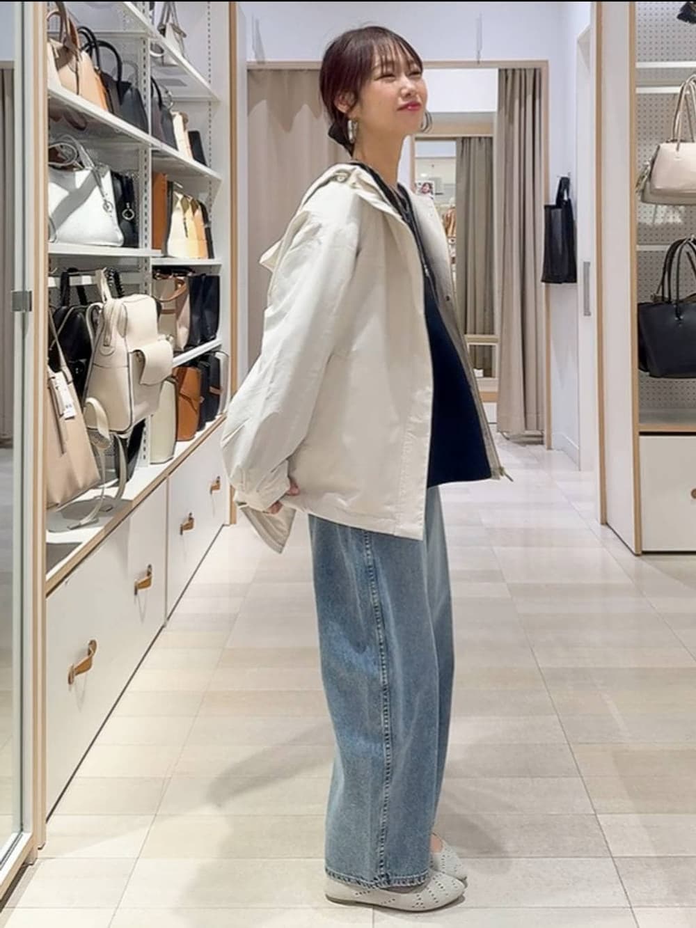 ベージュ系のトートバッグ、ベージュ系のマウンテンパーカー、ブルー系のデニムパンツを着用したレディースの春コーディネートの3枚目の写真