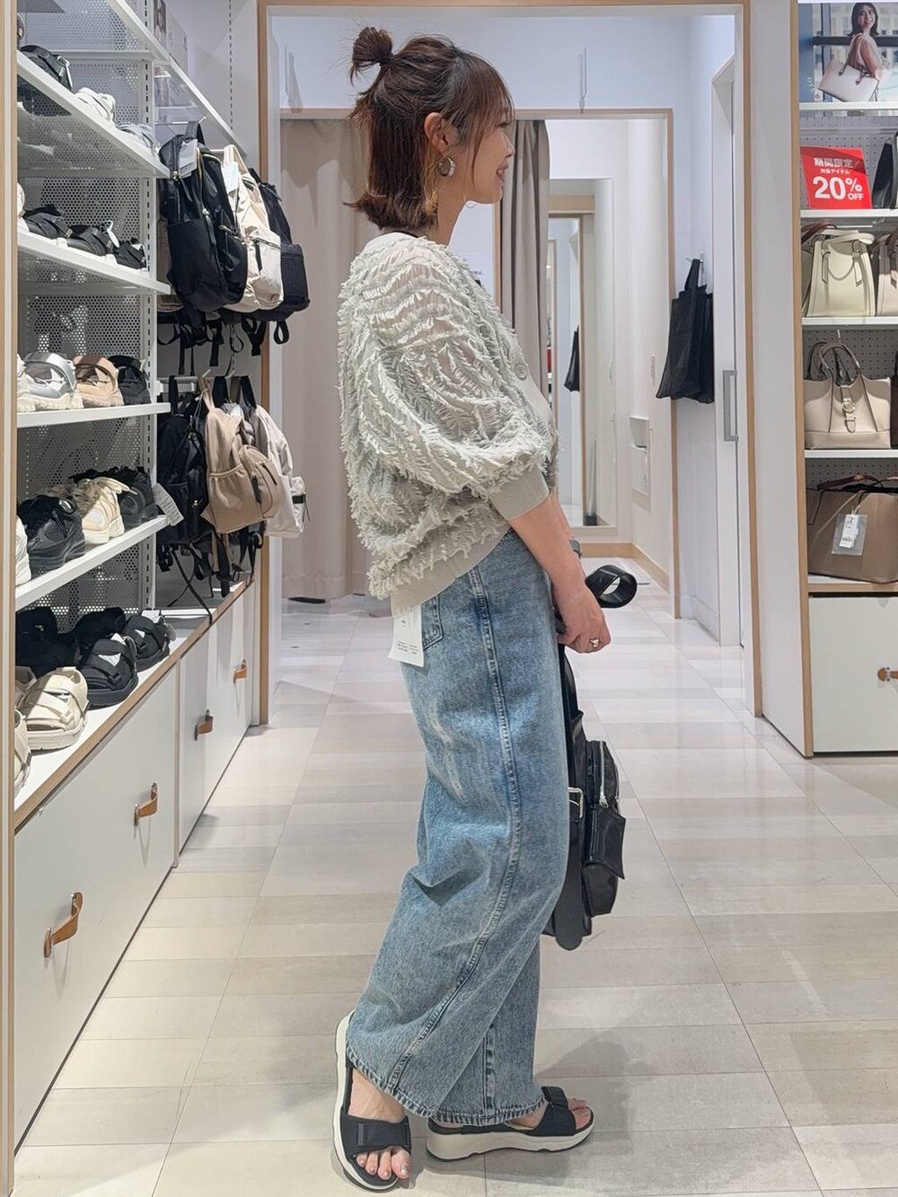 ブルー系のデニムパンツ、ブラック系のショルダーバッグ、ブラック系のタンクトップを着用したレディースの春コーディネートの3枚目の写真