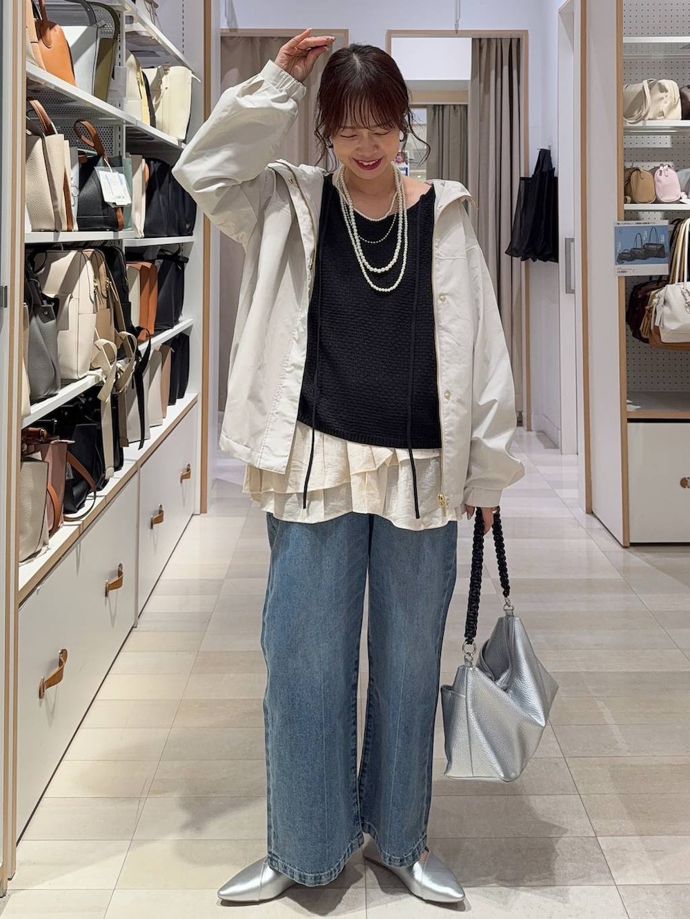 ホワイト系のパンプス、ブルー系のデニムパンツ、ベージュ系のマウンテンパーカーを着用したレディースの春コーディネートの2枚目の写真