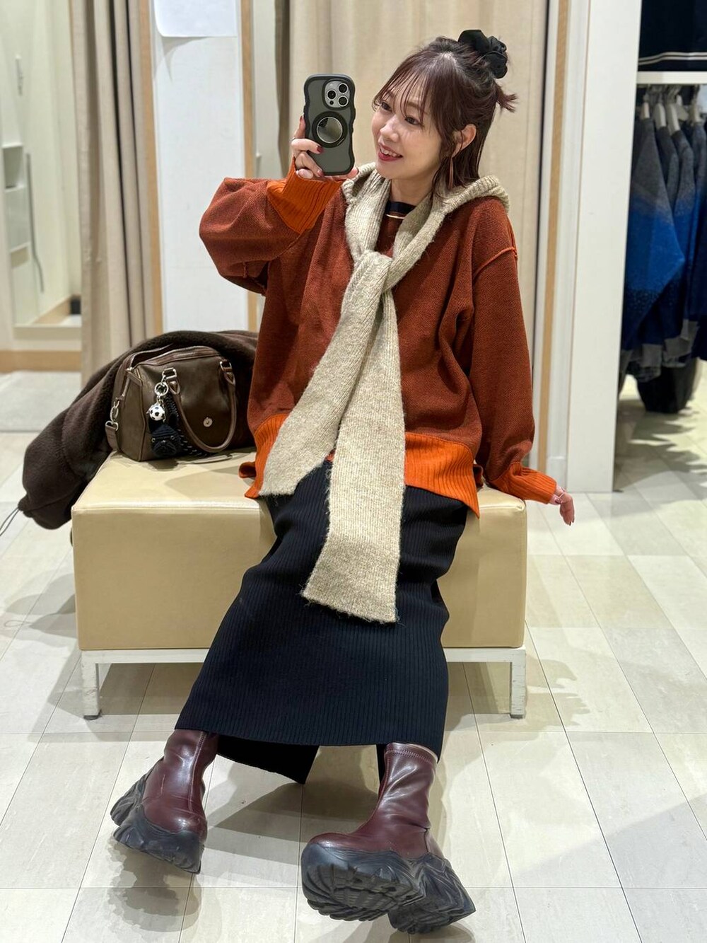 ブラック系のショルダーバッグ、ブルー系のチェスターコート、イエロー系のブーツを着用したレディースの冬コーディネートの5枚目の写真