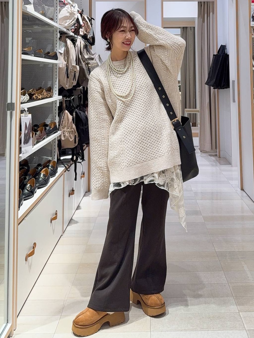 ブラック系のショルダーバッグ、イエロー系のブーツ、ホワイト系のニット/セーターを着用したレディースの冬コーディネートの4枚目の写真