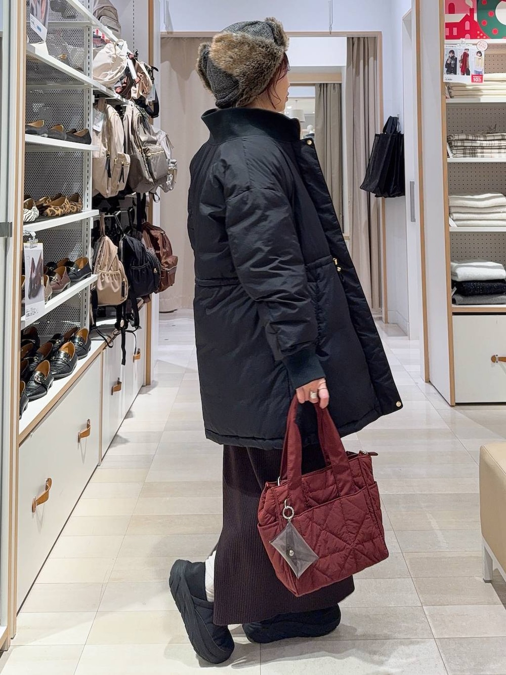 レッド系のトートバッグ、ブラック系のダウンジャケット/コート、レッド系のニット/セーターを着用したレディースの冬コーディネートの6枚目の写真