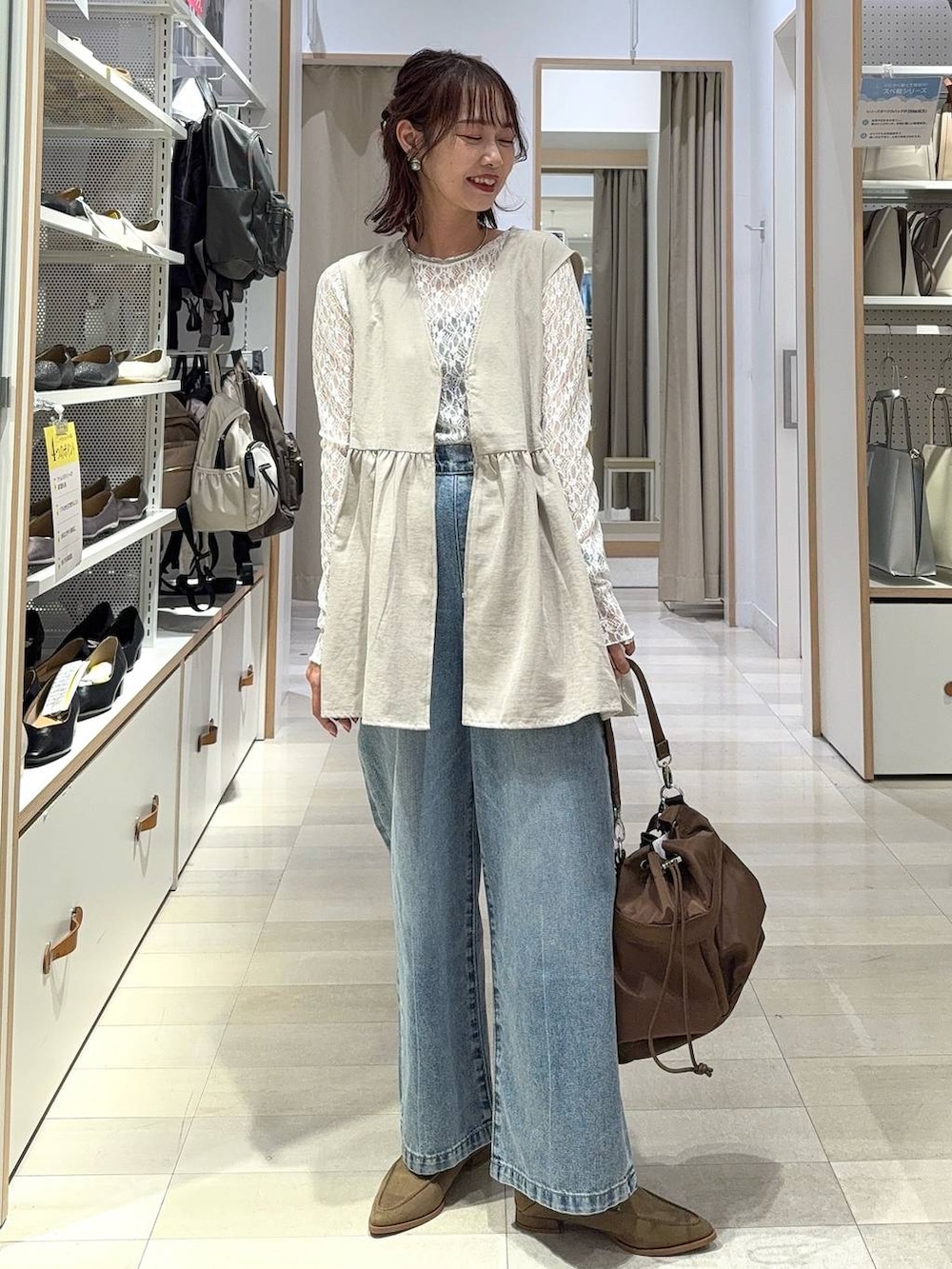 ブルー系のデニムパンツ、ブラウン系のトートバッグ、ブラウン系のシャツ/ブラウスを着用したレディースの秋コーディネートの2枚目の写真