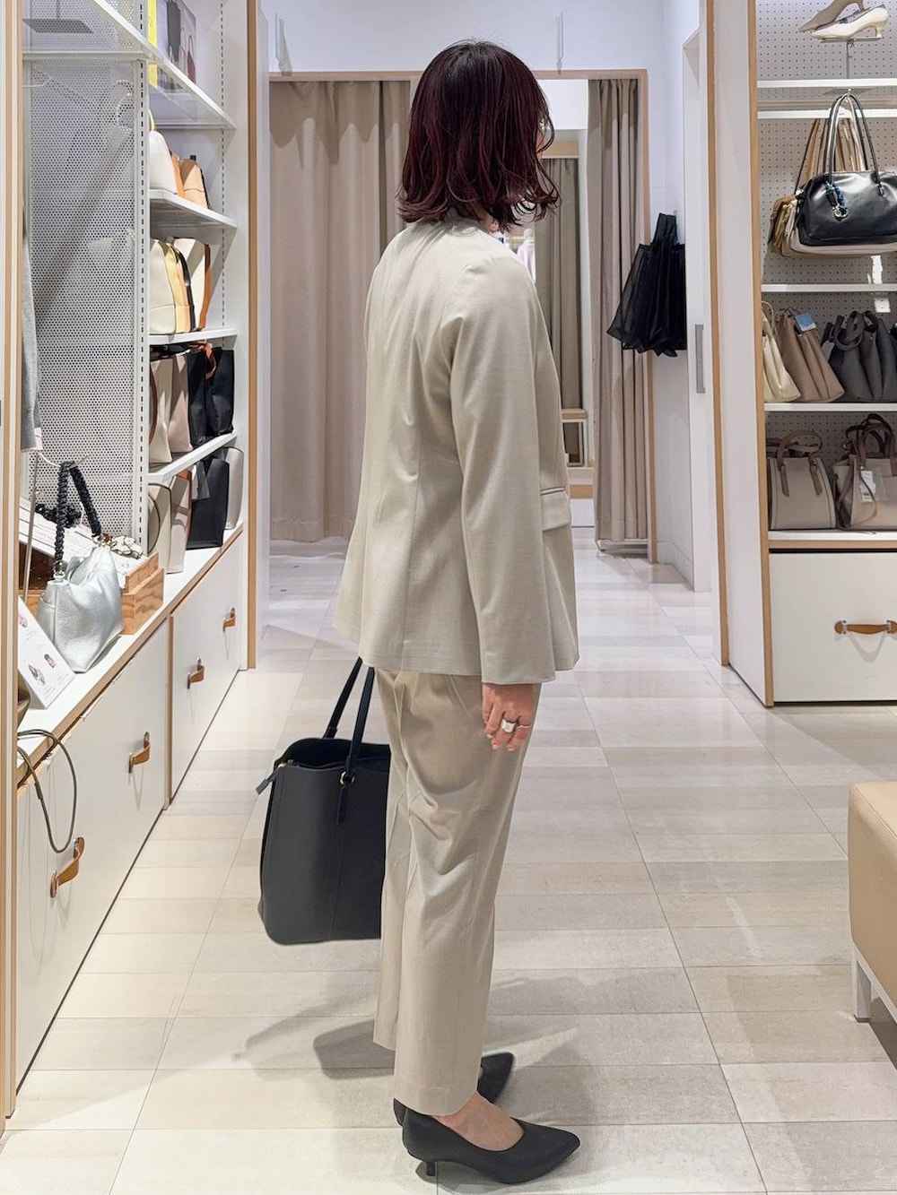 ベージュ系のスラックス、ベージュ系のノーカラージャケット、グレー系のトートバッグを着用したレディースの冬コーディネートの4枚目の写真