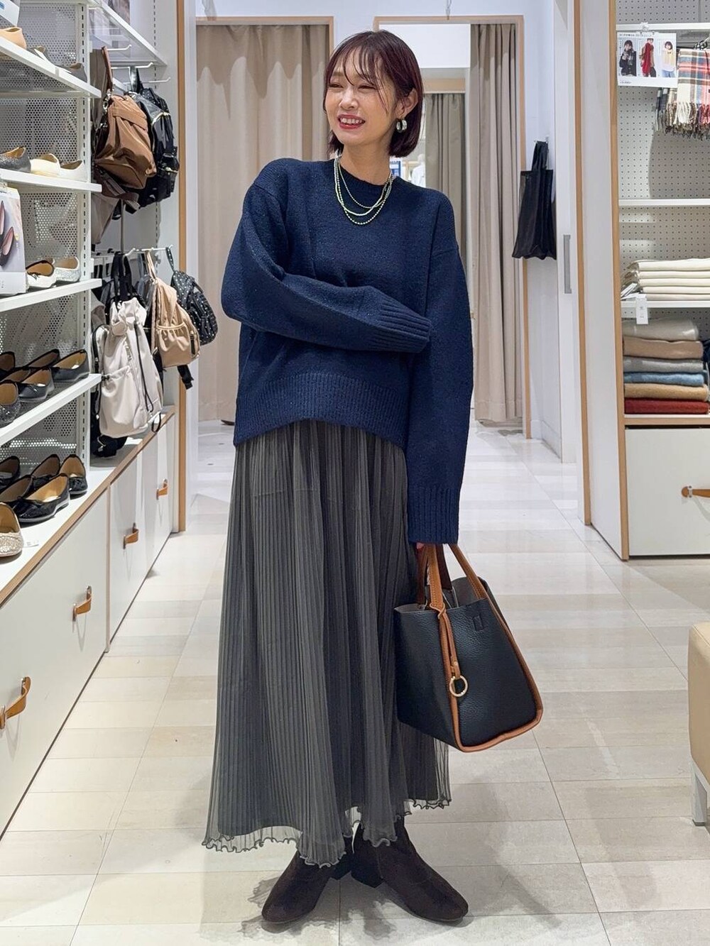 ブラック系のトートバッグ、ブラウン系のノーカラージャケット、シルバー系のネックレスを着用したレディースの秋コーディネートの2枚目の写真