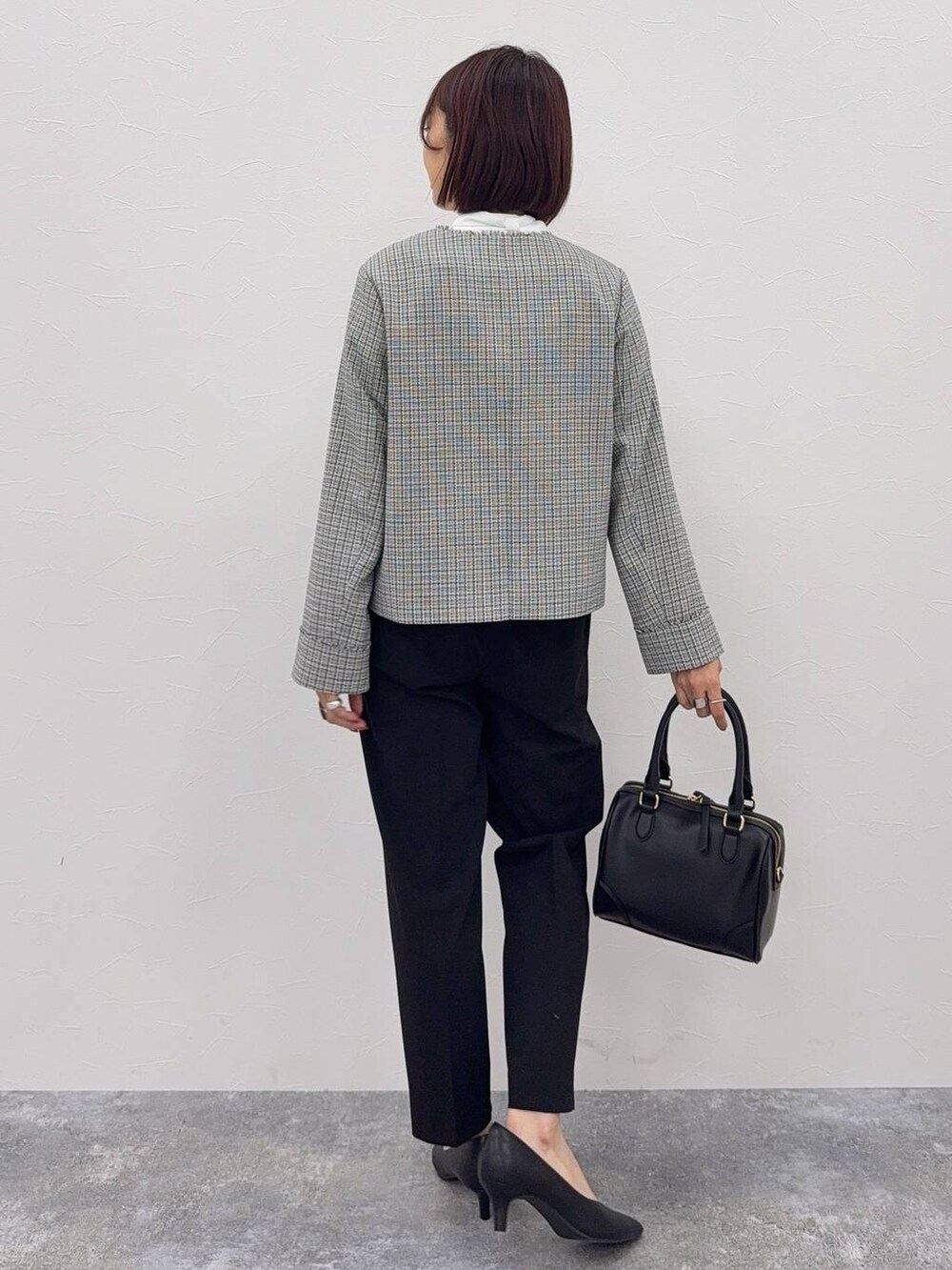 ブラック系のスラックス、ブラック系のボストンバッグ、ホワイト系のシャツ/ブラウスを着用したレディースの秋コーディネートの2枚目の写真