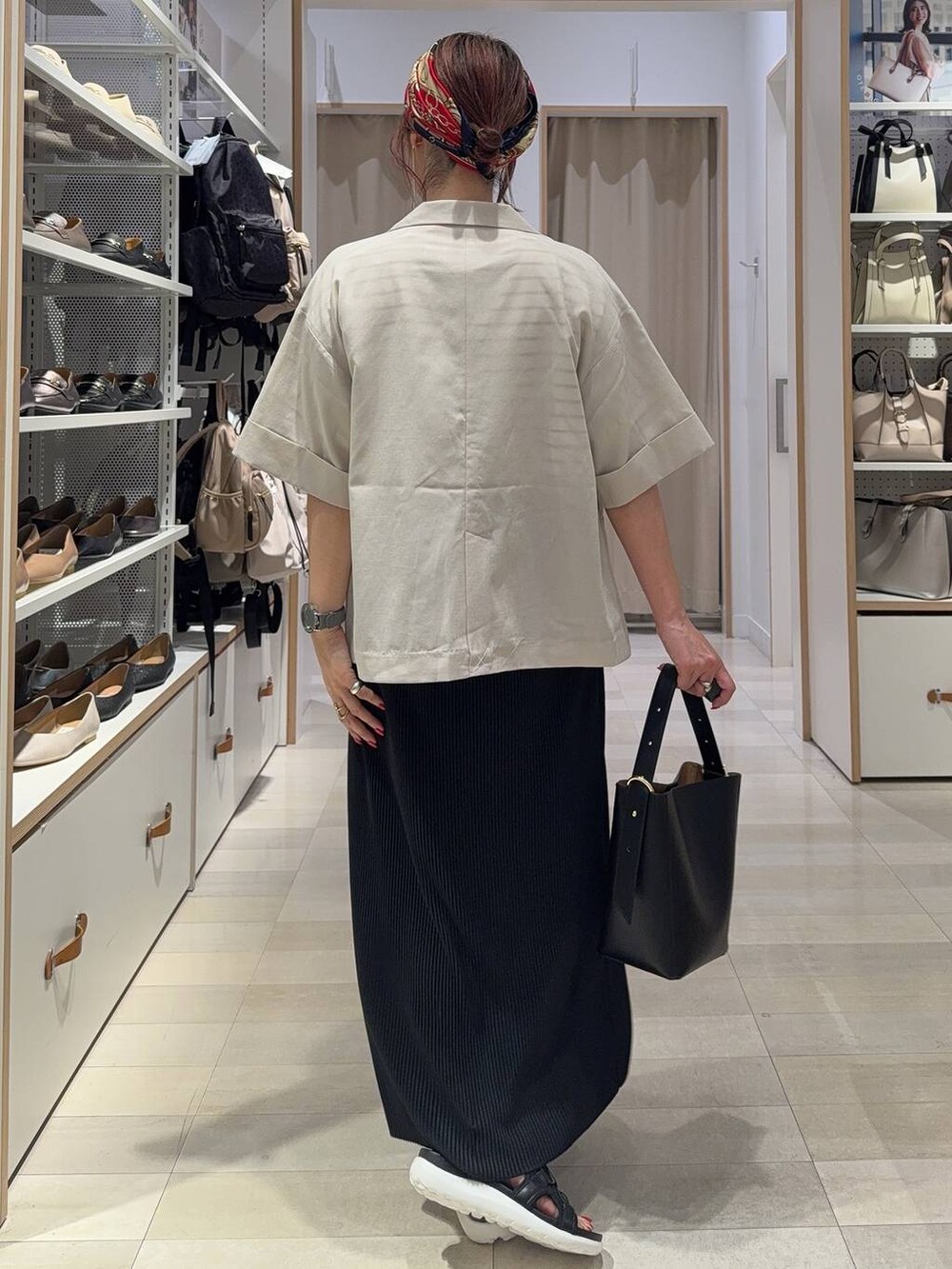 ブラック系のショルダーバッグ、ブラック系のスカート、ブラック系のサンダルを着用したレディースの夏コーディネートの6枚目の写真