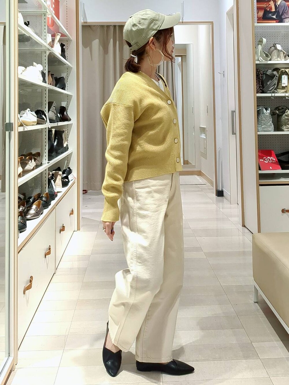 ベージュ系のデニムパンツ、ブラック系のショルダーバッグ、イエロー系のカーディガン/ボレロを着用したレディースの春コーディネートの6枚目の写真