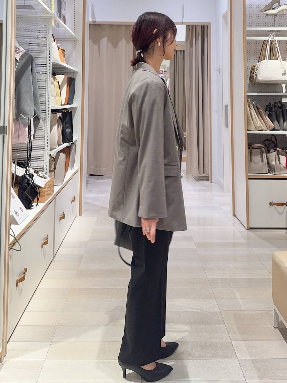 ブラック系のスラックス、ブラック系のトートバッグ、ブラウン系のテーラードジャケットを着用したレディースの冬コーディネートの3枚目の写真