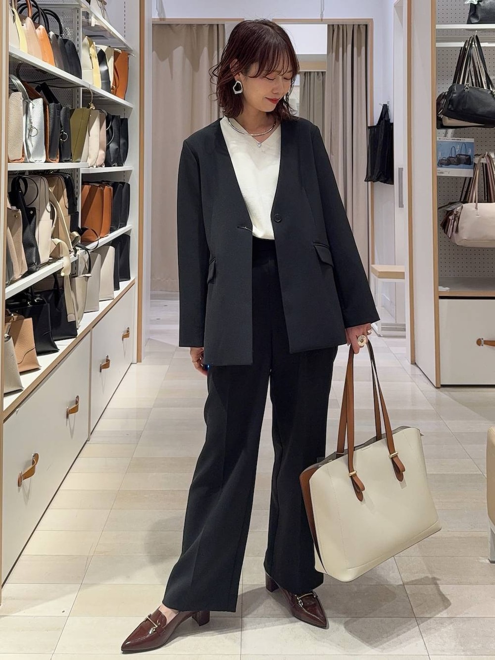 ブラック系のその他パンツ、ブラック系のテーラードジャケット、ホワイト系のトートバッグを着用したレディースの春コーディネートの2枚目の写真