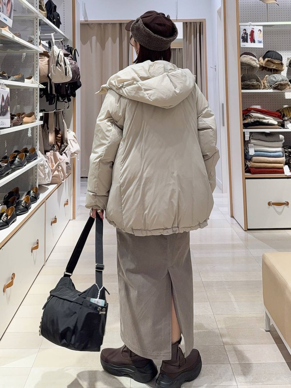 ブラック系のショルダーバッグ、ベージュ系のダウンジャケット/コート、ブラウン系のスカートを着用したレディースの秋コーディネートの4枚目の写真