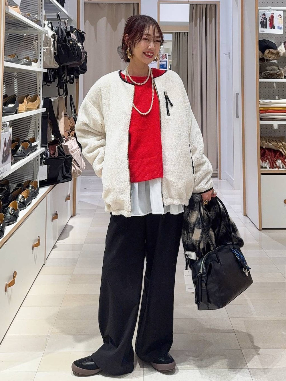 ブラック系のスニーカー、ブラウン系のボストンバッグ、ホワイト系のブルゾンを着用したレディースの冬コーディネートの2枚目の写真