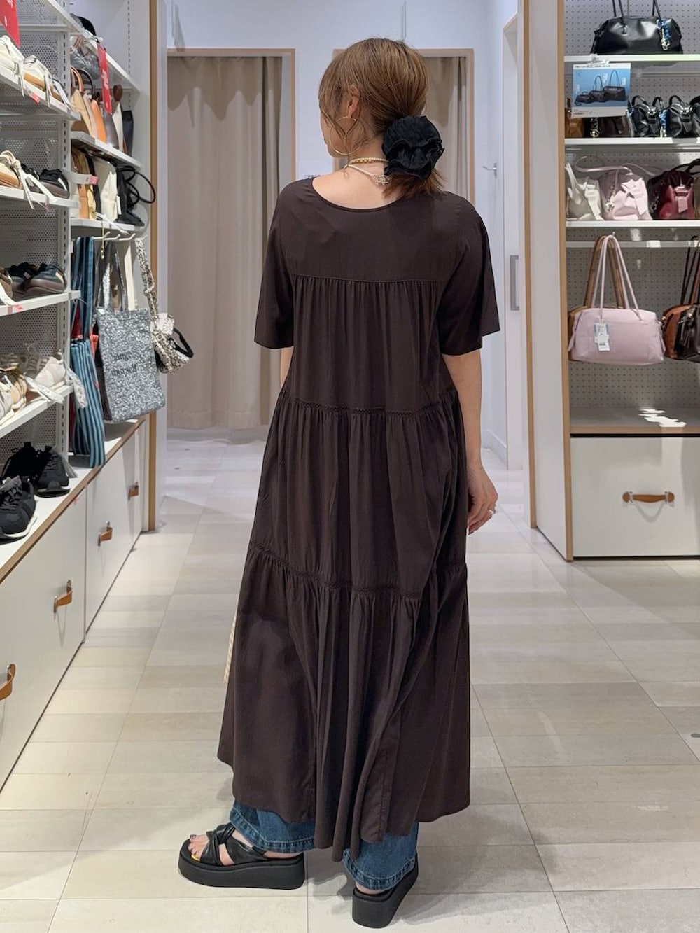 ブルー系のデニムパンツ、ブラウン系のワンピース、ブラック系のサンダルを着用したレディースの夏コーディネートの7枚目の写真