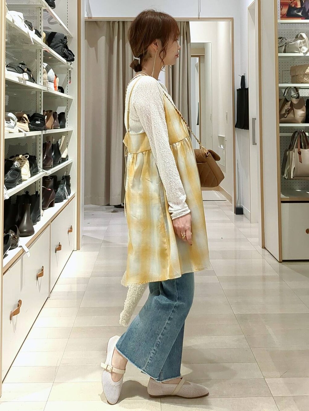 ブルー系のデニムパンツ、ベージュ系のショルダーバッグ、ホワイト系のTシャツ/カットソーを着用したレディースの春コーディネートの6枚目の写真