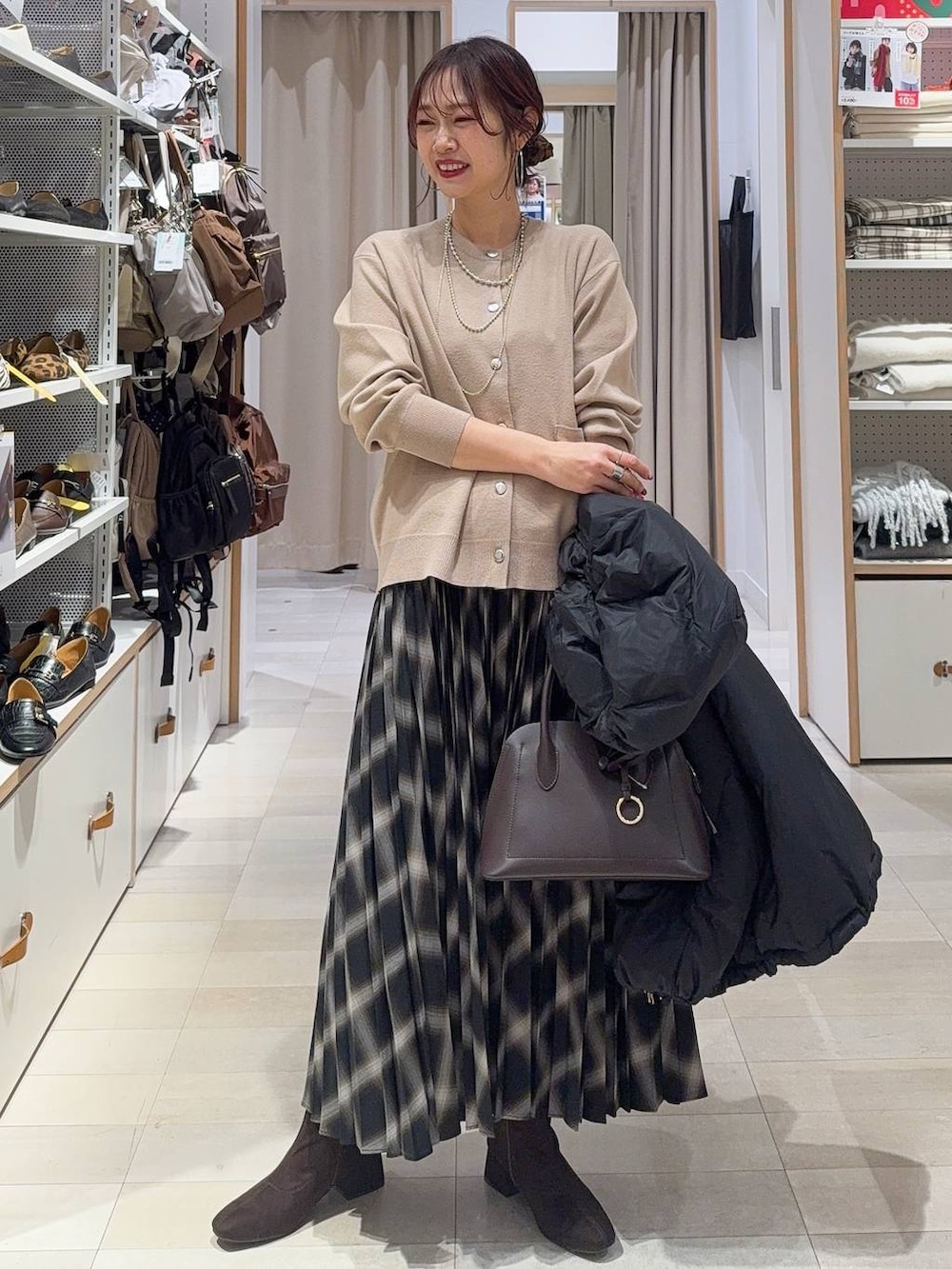 ブラウン系のショルダーバッグ、ブラック系のダウンジャケット/コート、ベージュ系のカーディガン/ボレロを着用したレディースの冬コーディネートの2枚目の写真