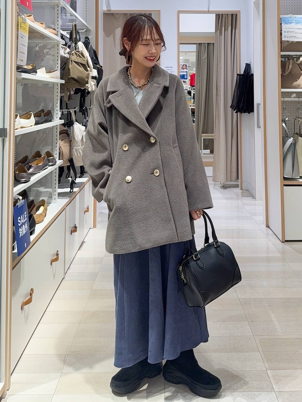 ブラウン系のボストンバッグ、ブルー系のデニムパンツ、ブラウン系のチェスターコートを着用したレディースの秋コーディネートの3枚目の写真