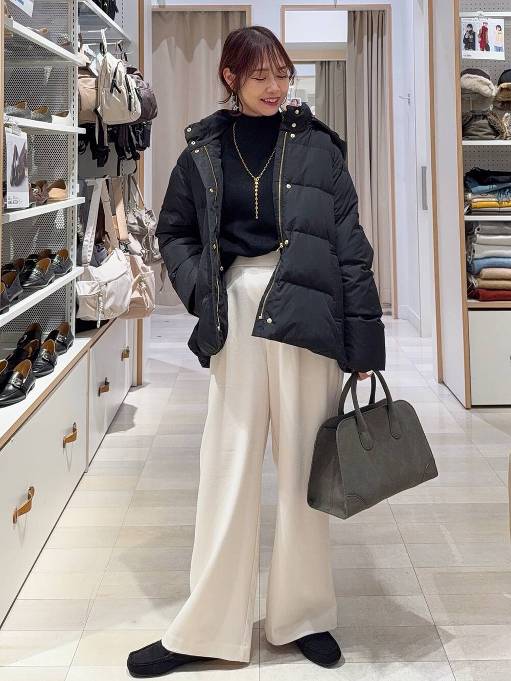 ブラック系のダウンジャケット/コート、グリーン系のショルダーバッグ、ブラック系のニット/セーターを着用したレディースの秋コーディネートの2枚目の写真