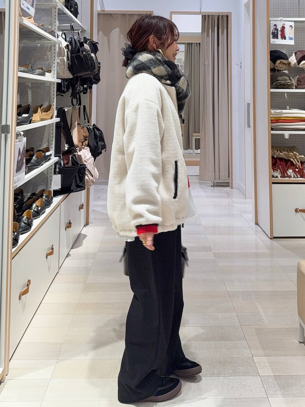 ブラック系のスニーカー、ブラウン系のボストンバッグ、ホワイト系のブルゾンを着用したレディースの冬コーディネートの4枚目の写真