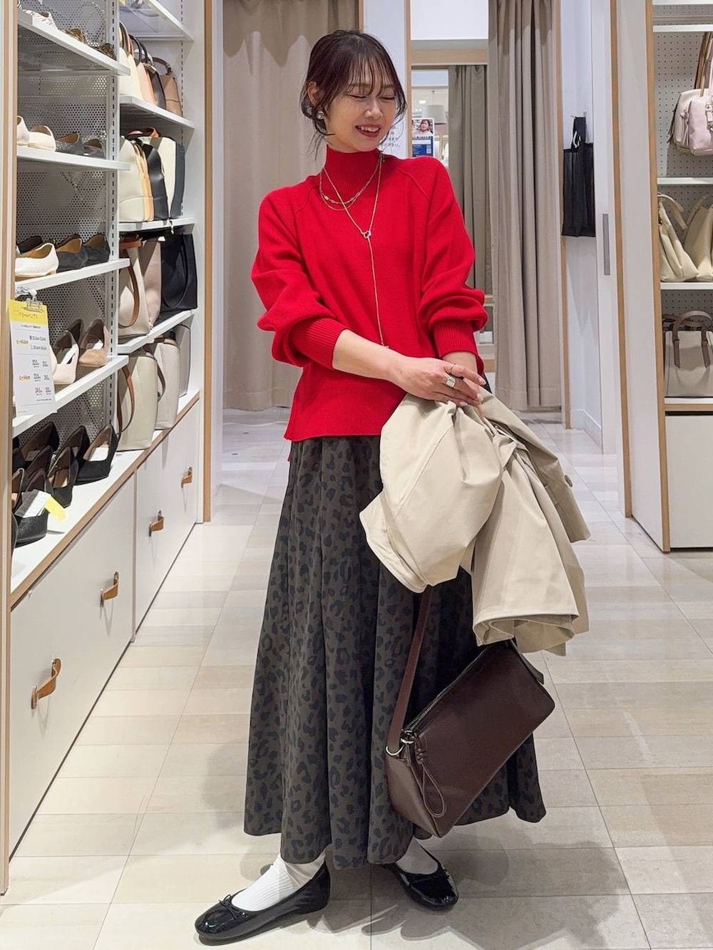 ブラック系のバレエシューズ、レッド系のニット/セーター、ベージュ系のトレンチコートを着用したレディースの冬コーディネートの2枚目の写真
