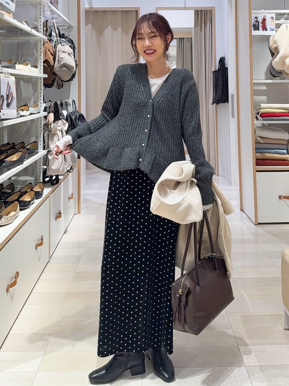 ブラウン系のボストンバッグ、ホワイト系のTシャツ/カットソー、ブラック系のスカートを着用したレディースの秋コーディネートの4枚目の写真