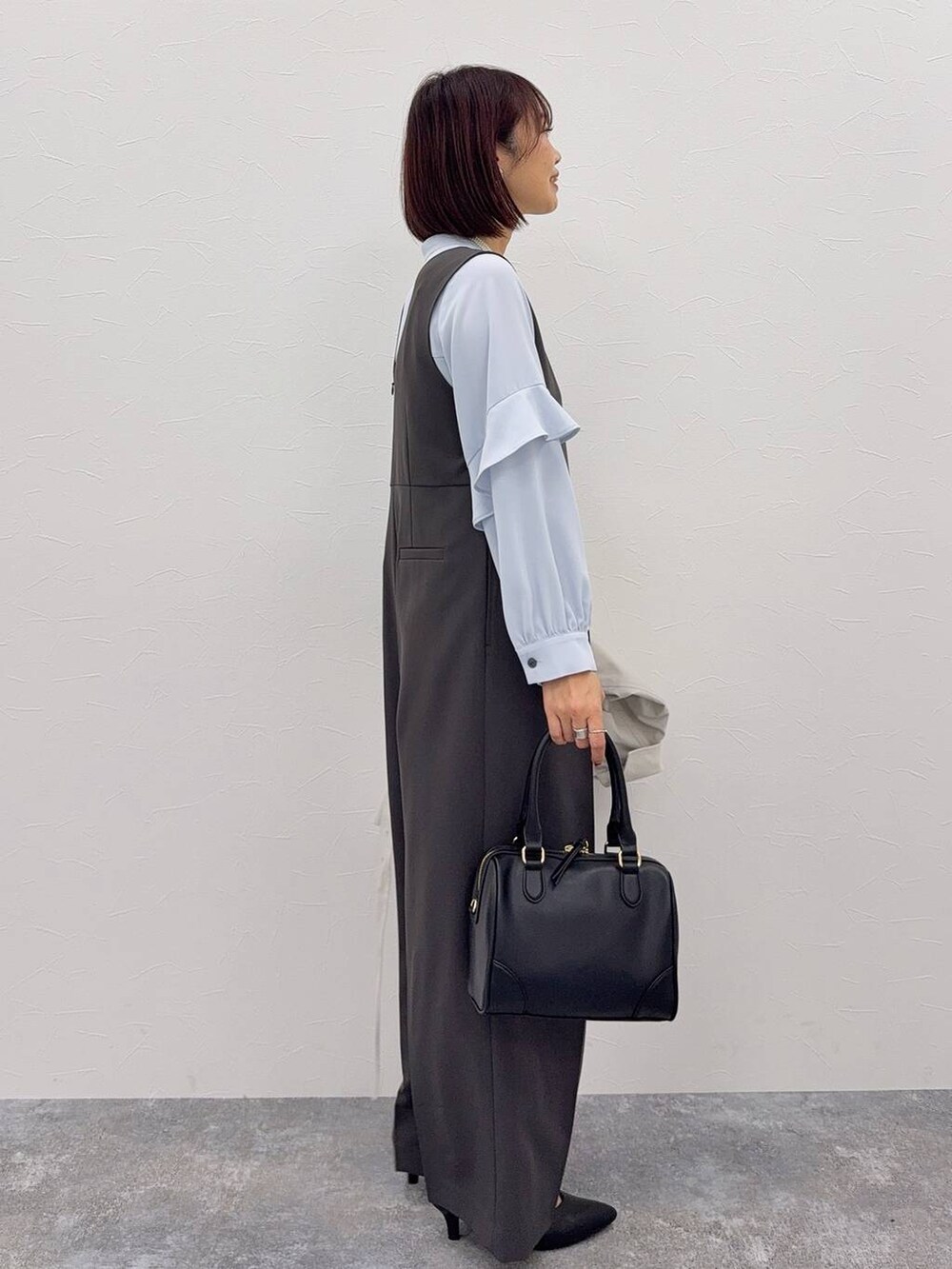 グレー系のセットアップ、ブラック系のボストンバッグ、その他のネックレスを着用したレディースの秋コーディネートの3枚目の写真