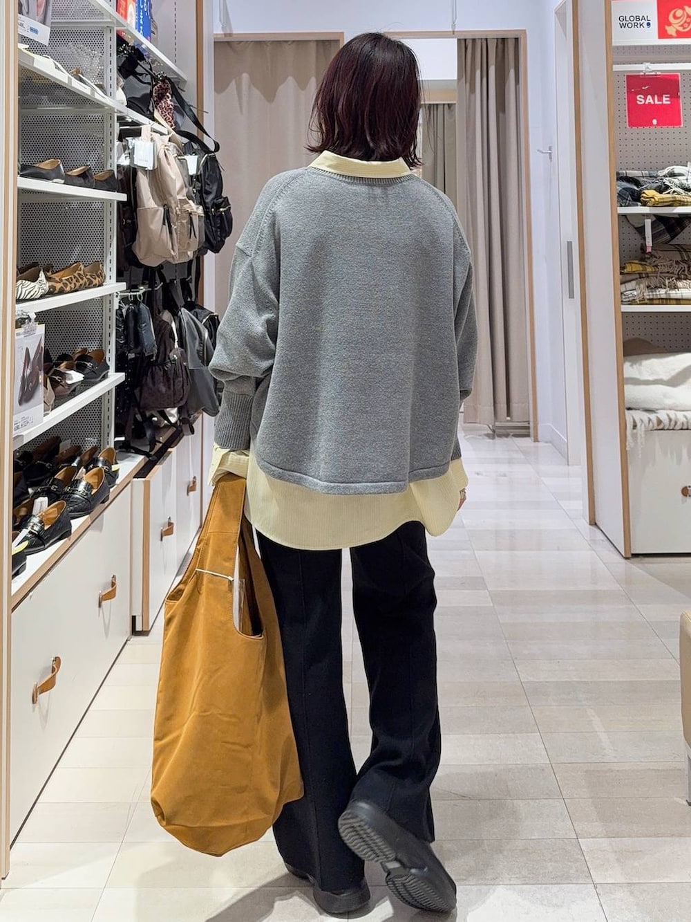 グレー系のニット/セーター、イエロー系のシャツ/ブラウス、ベージュ系のトートバッグを着用したレディースの冬コーディネートの4枚目の写真