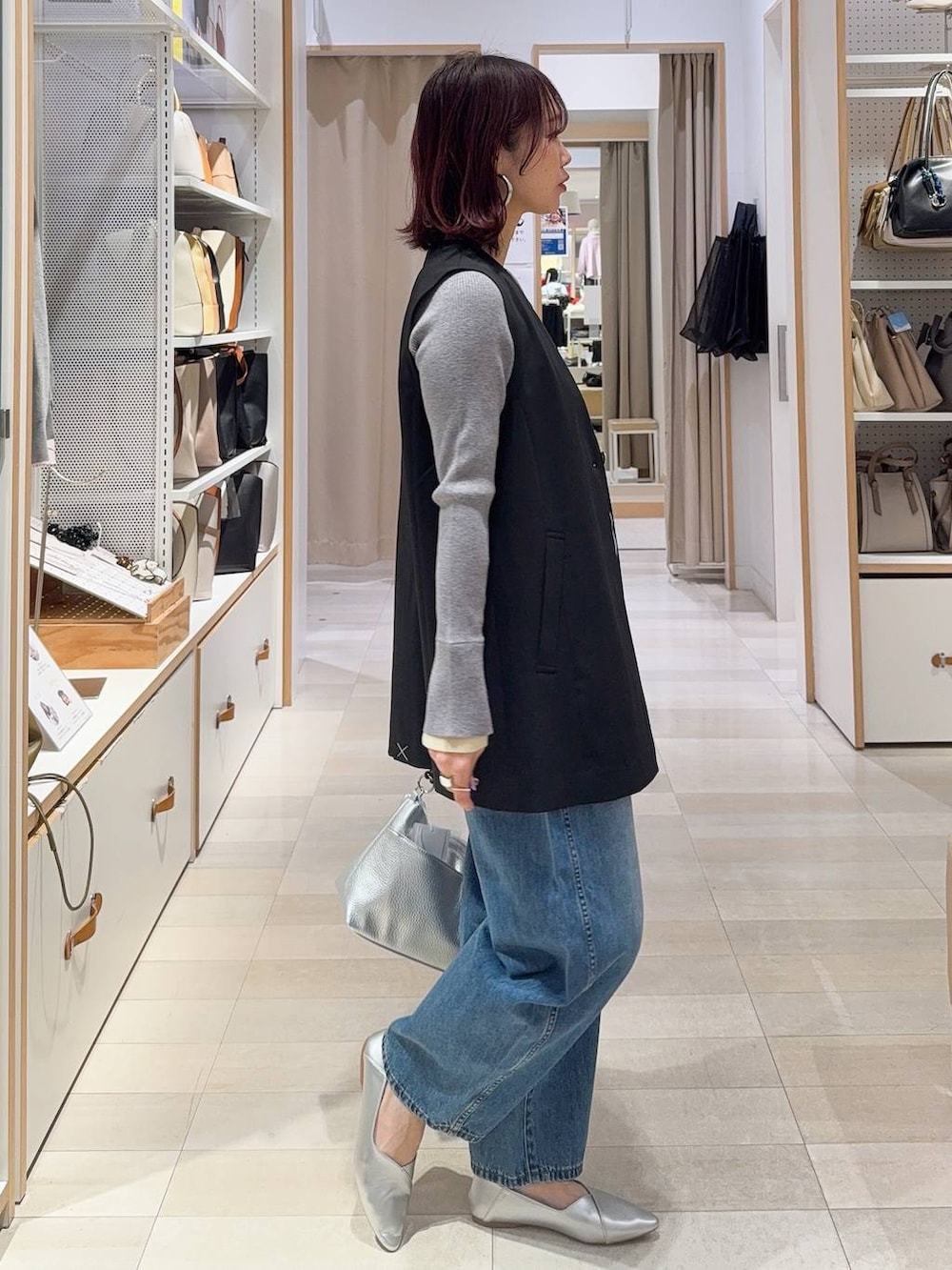 シルバー系のパンプス、ブラック系のその他アウター、ブルー系のデニムパンツを着用したレディースの冬コーディネートの6枚目の写真