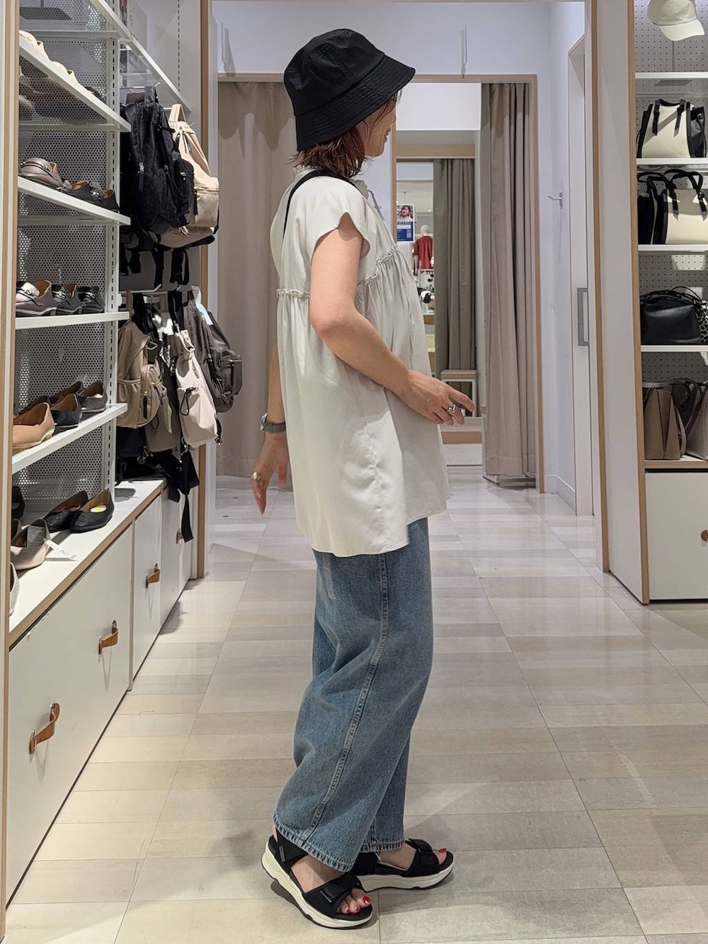 ブルー系のデニムパンツ、ブラック系のショルダーバッグ、ブラック系のサンダルを着用したレディースの夏コーディネートの3枚目の写真