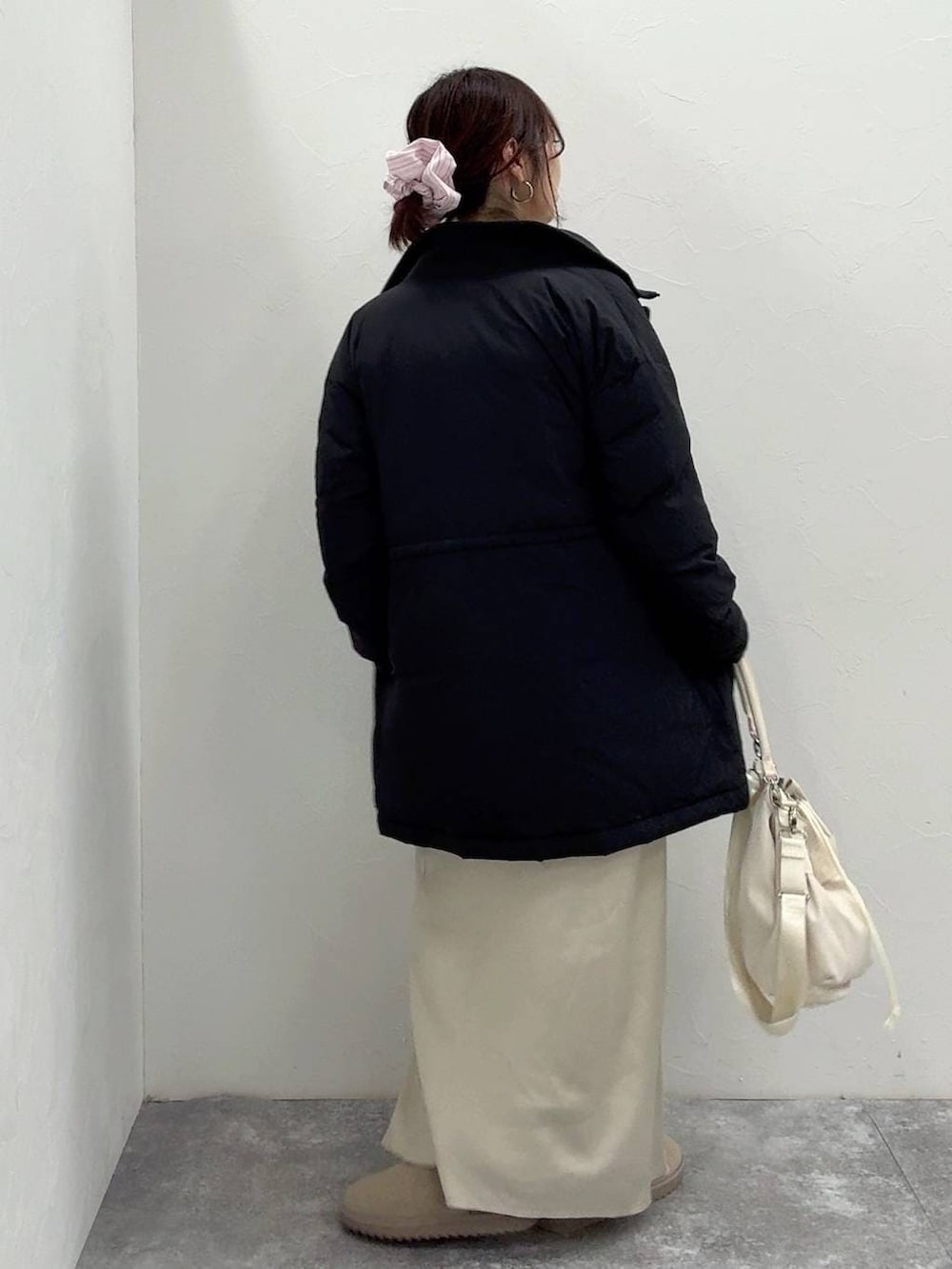 ホワイト系のショルダーバッグ、ブラック系のダウンジャケット/コート、ホワイト系のスカートを着用したレディースの冬コーディネートの5枚目の写真