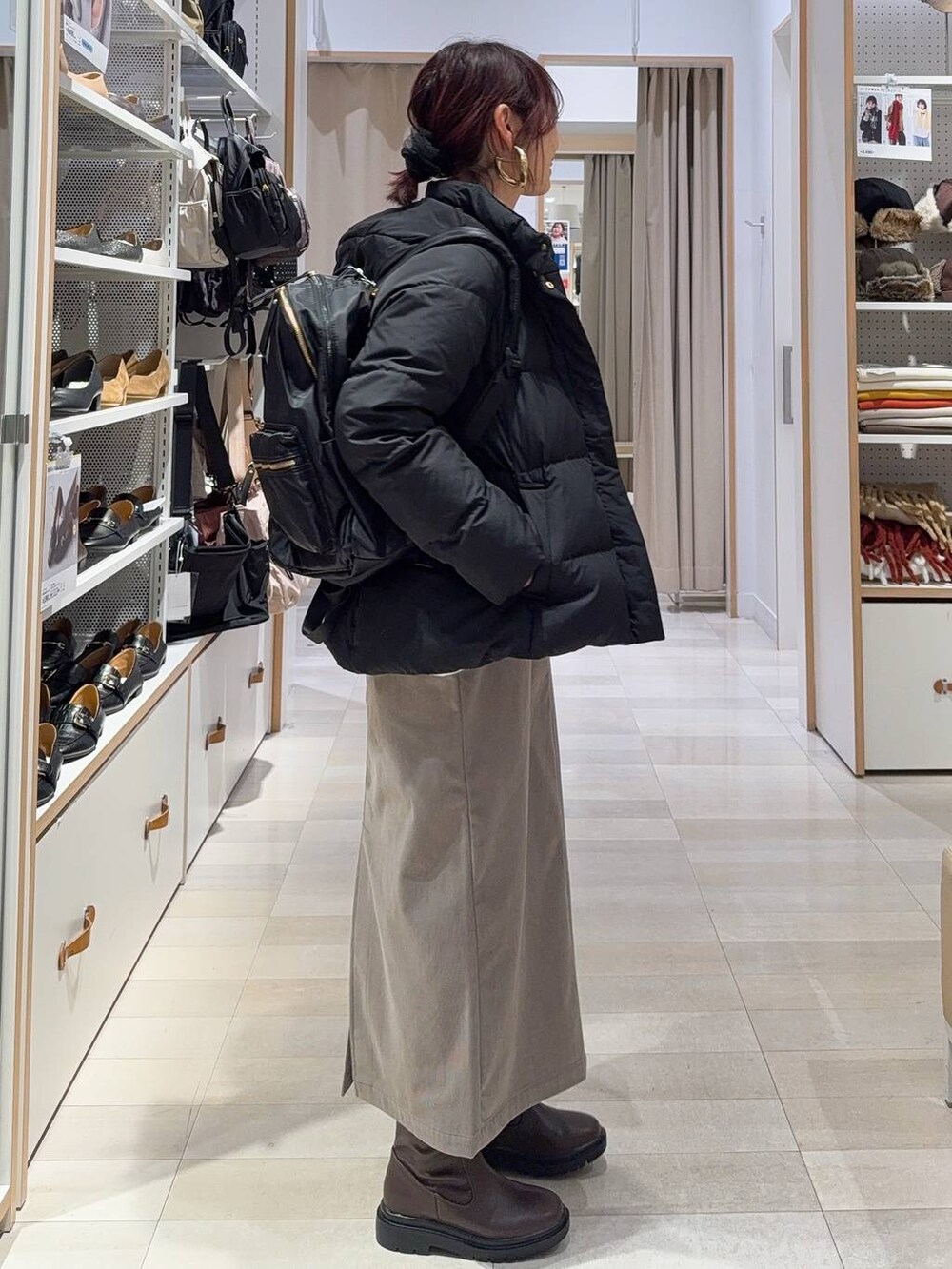 ブラック系のダウンジャケット/コート、ブラウン系のスカート、ホワイト系のニット/セーターを着用したレディースの冬コーディネートの3枚目の写真