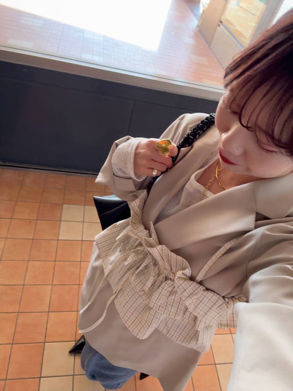 ベージュ系のテーラードジャケット、ホワイト系のTシャツ/カットソー、ブラウン系のキャミソールを着用したレディースの春コーディネートの3枚目の写真