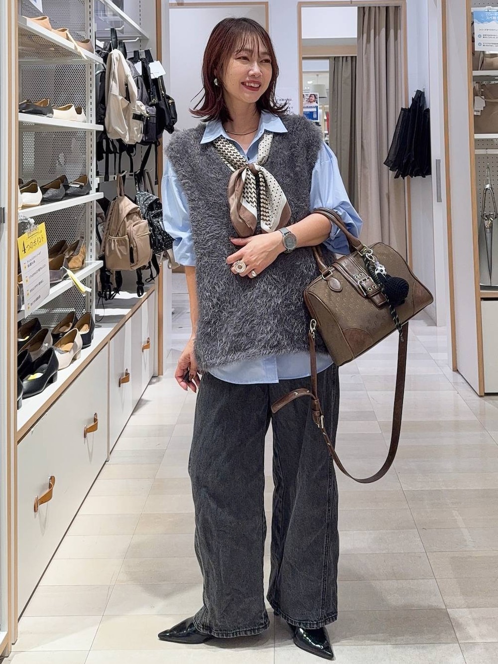 グリーン系のボストンバッグ、ホワイト系のブルゾン、グレー系のスカートを着用したレディースの秋コーディネートの4枚目の写真