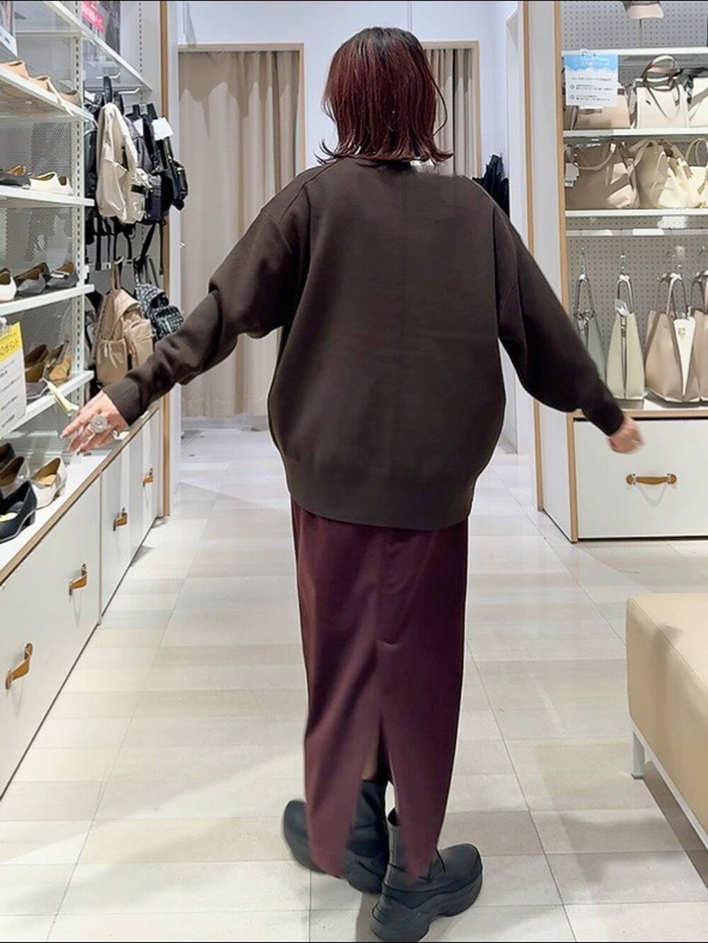 ブラウン系のボストンバッグ、グレー系のチェスターコート、レッド系のスカートを着用したレディースの秋コーディネートの7枚目の写真