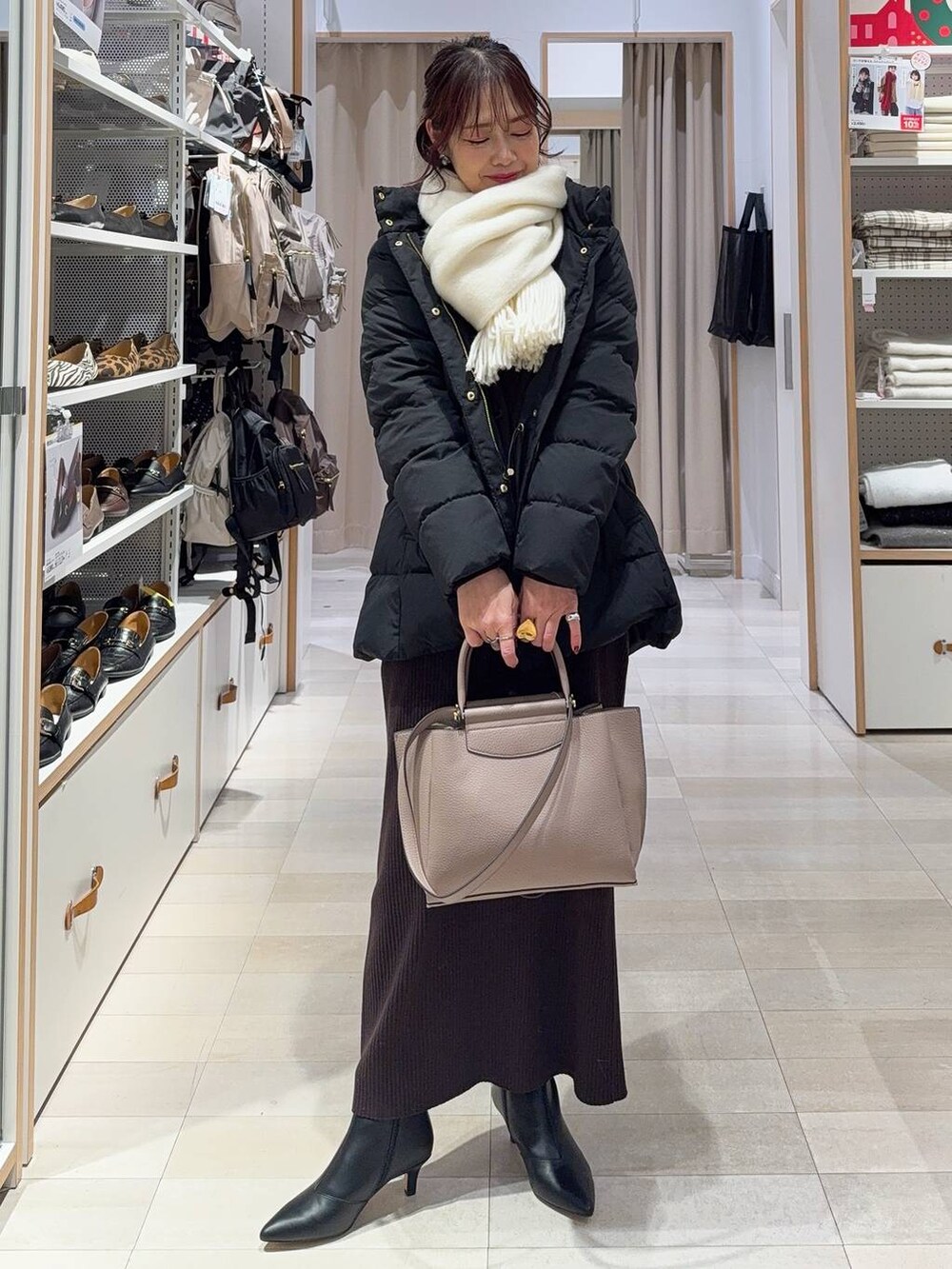 ブラック系のダウンジャケット/コート、ブラウン系のワンピース、ブラック系のブーツを着用したレディースの冬コーディネートの3枚目の写真