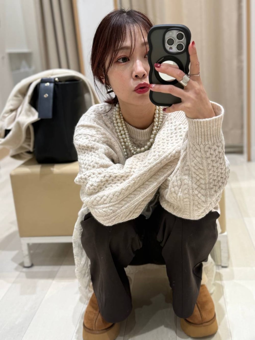 ブラック系のショルダーバッグ、イエロー系のブーツ、ホワイト系のニット/セーターを着用したレディースの冬コーディネートの2枚目の写真