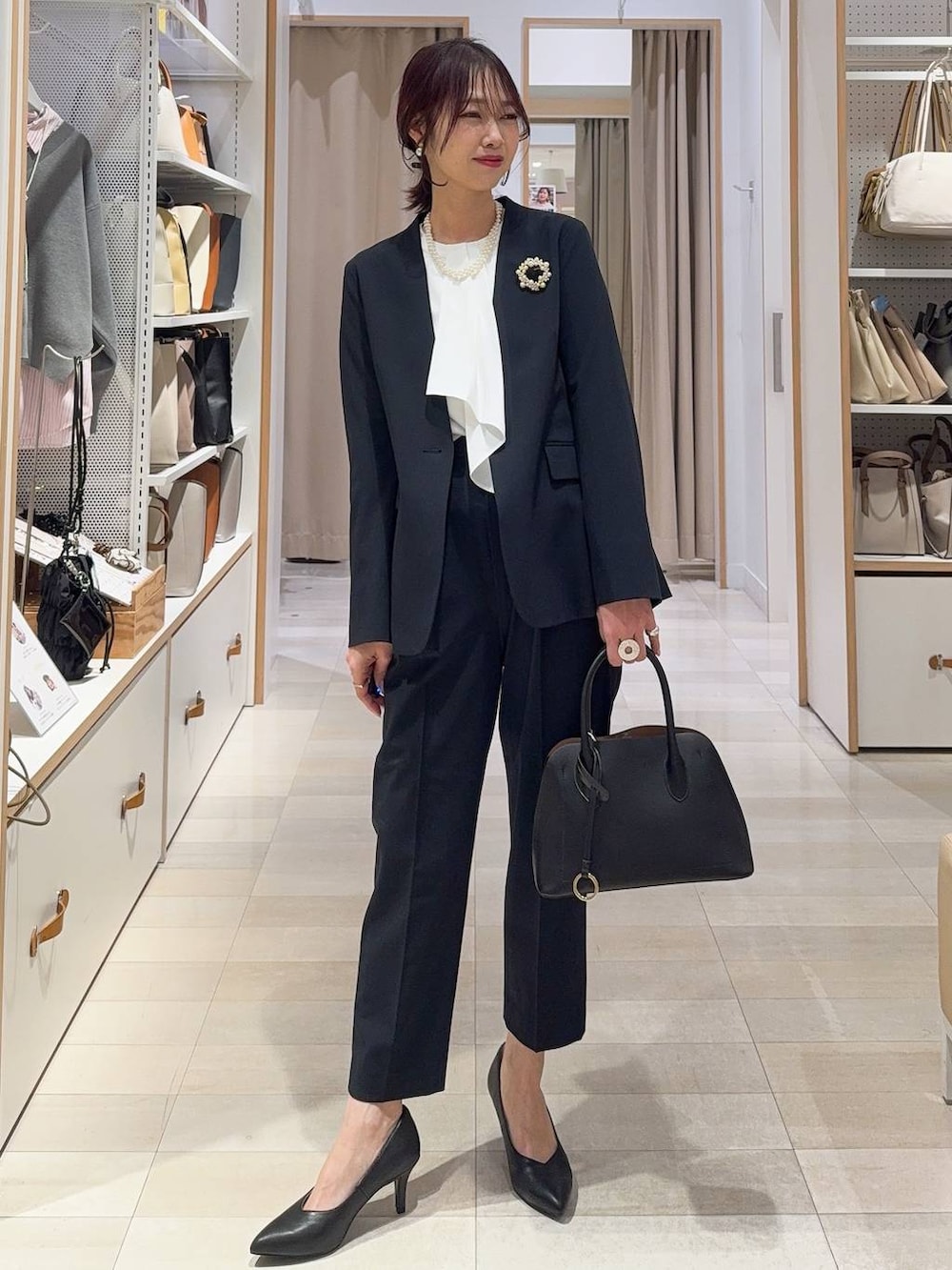 ブラック系のショルダーバッグ、ブルー系のスラックス、ブルー系のノーカラージャケットを着用したレディースの冬コーディネートの3枚目の写真