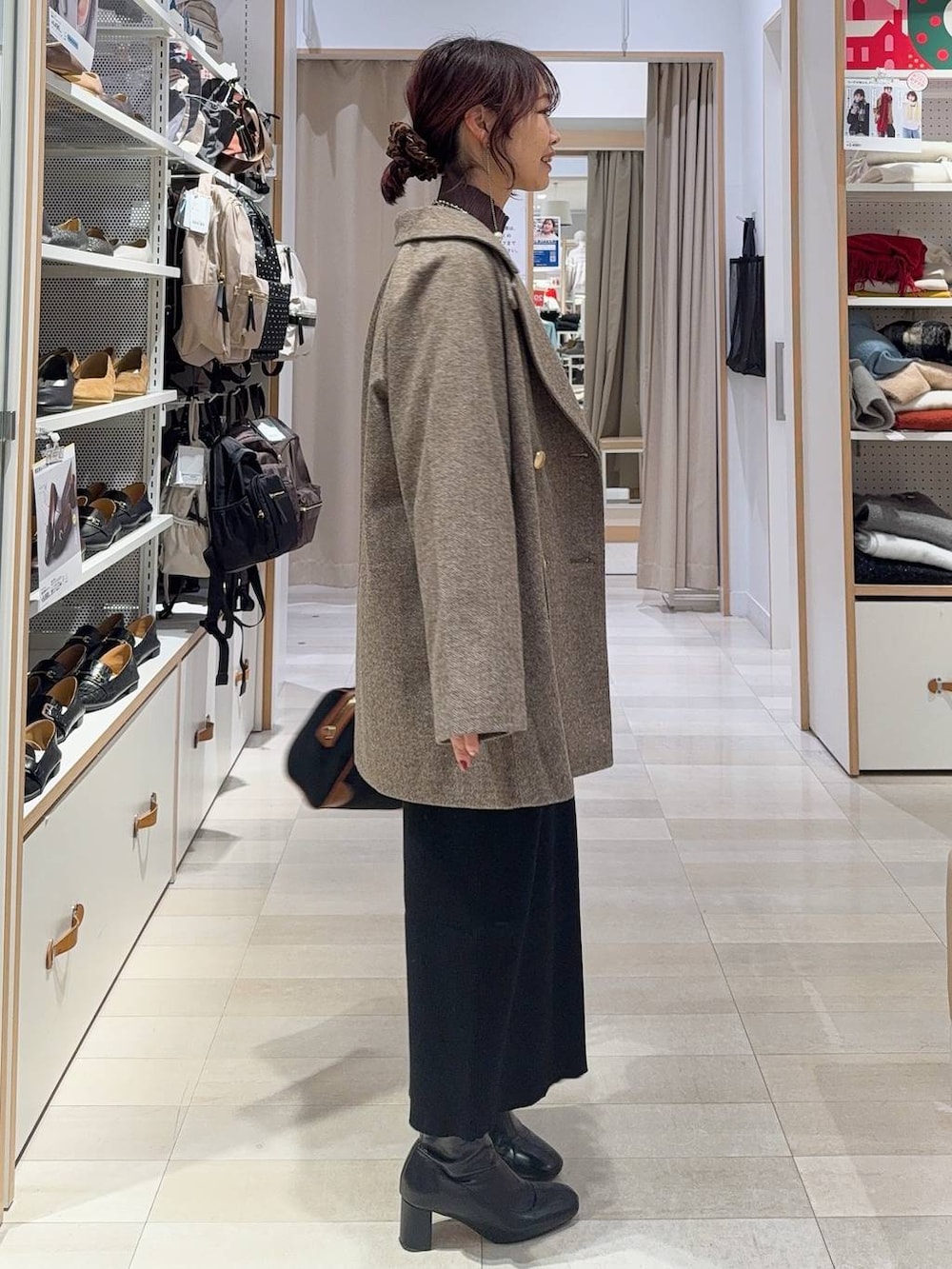 ブラウン系のチェスターコート、ホワイト系のTシャツ/カットソー、ブラウン系のニット/セーターを着用したレディースの冬コーディネートの5枚目の写真