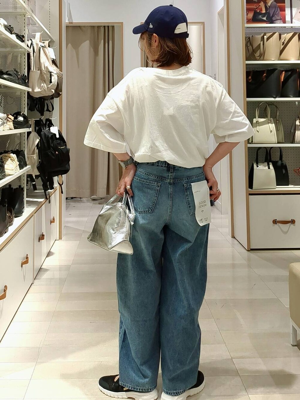 ブラック系のスニーカー、シルバー系のショルダーバッグ、ブルー系のデニムパンツを着用したレディースの春コーディネートの7枚目の写真