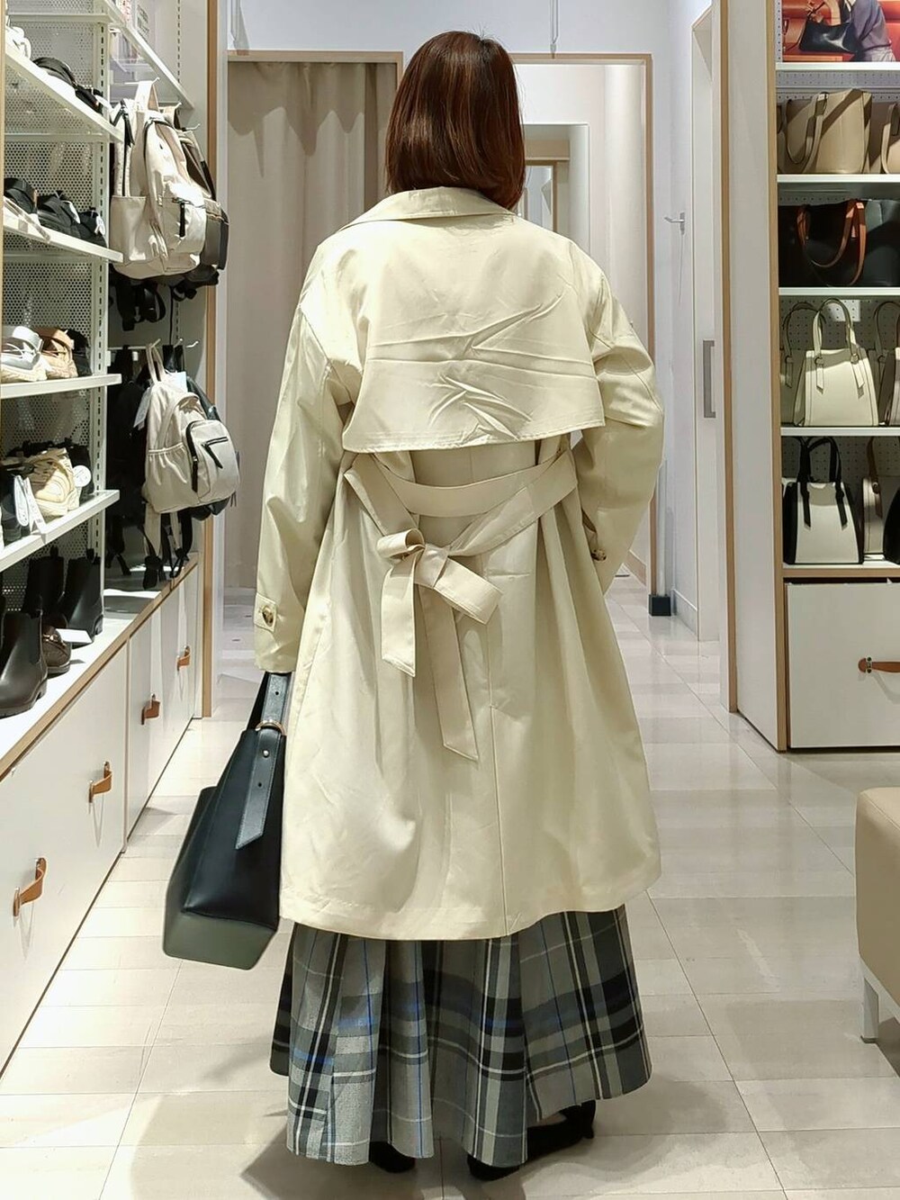 イエロー系のトレンチコート、ブルー系のニット/セーター、ブラック系のショルダーバッグを着用したレディースの春コーディネートの5枚目の写真