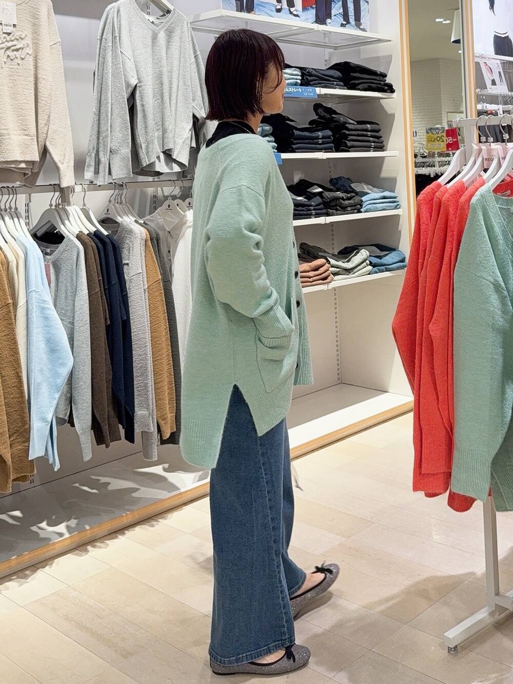 グレー系のバレエシューズ、シルバー系のハンドバッグ、ブルー系のデニムパンツを着用したレディースの秋コーディネートの4枚目の写真