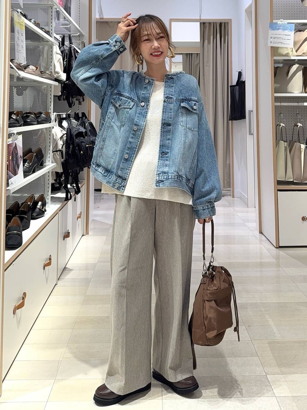 ブラック系のスニーカー、ブルー系のデニムジャケット、シルバー系のハンドバッグを着用したレディースの秋コーディネートの5枚目の写真