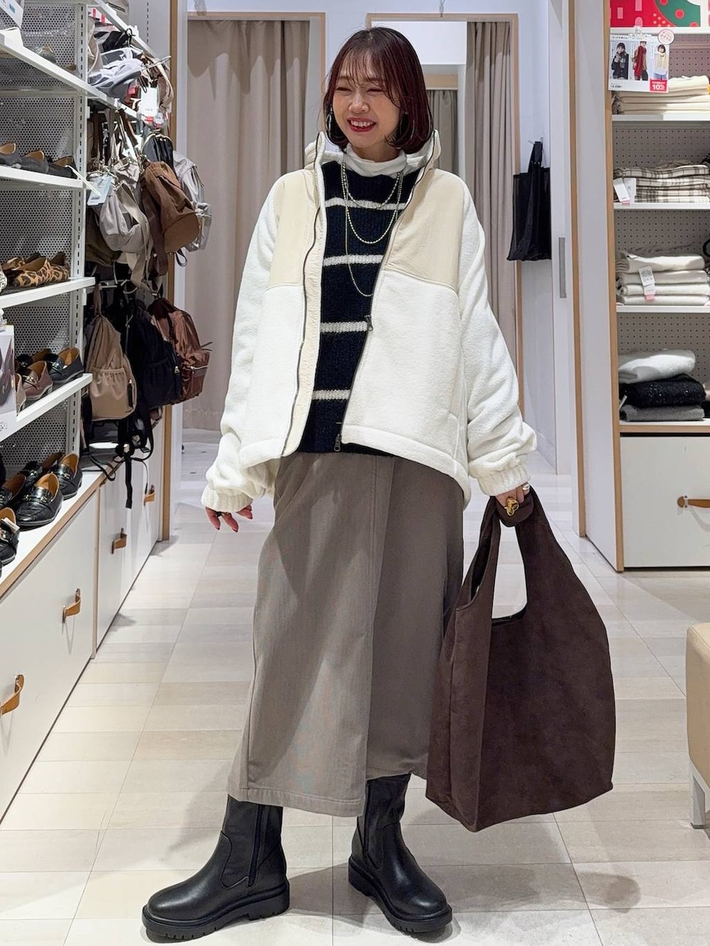 ブラウン系のスカート、ブラウン系のトートバッグ、ホワイト系のTシャツ/カットソーを着用したレディースの冬コーディネートの2枚目の写真