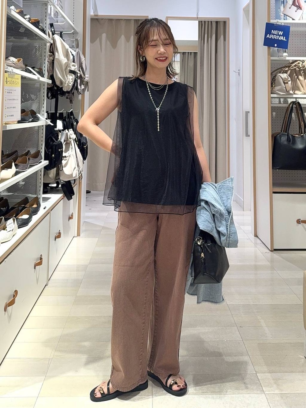 ブラウン系のサンダル、ブラウン系のデニムパンツ、ブラック系のハンドバッグを着用したレディースの夏コーディネートの3枚目の写真