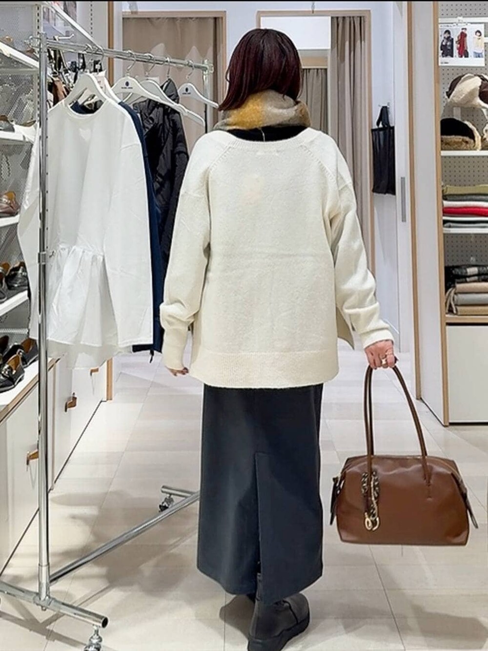 ブラウン系のボストンバッグ、ホワイト系のカーディガン/ボレロ、グレー系のスカートを着用したレディースの秋コーディネートの6枚目の写真