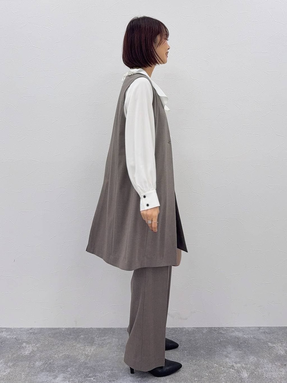 ベージュ系のショルダーバッグ、ブラック系のパンプス、ブラウン系のスラックスを着用したレディースの秋コーディネートの3枚目の写真