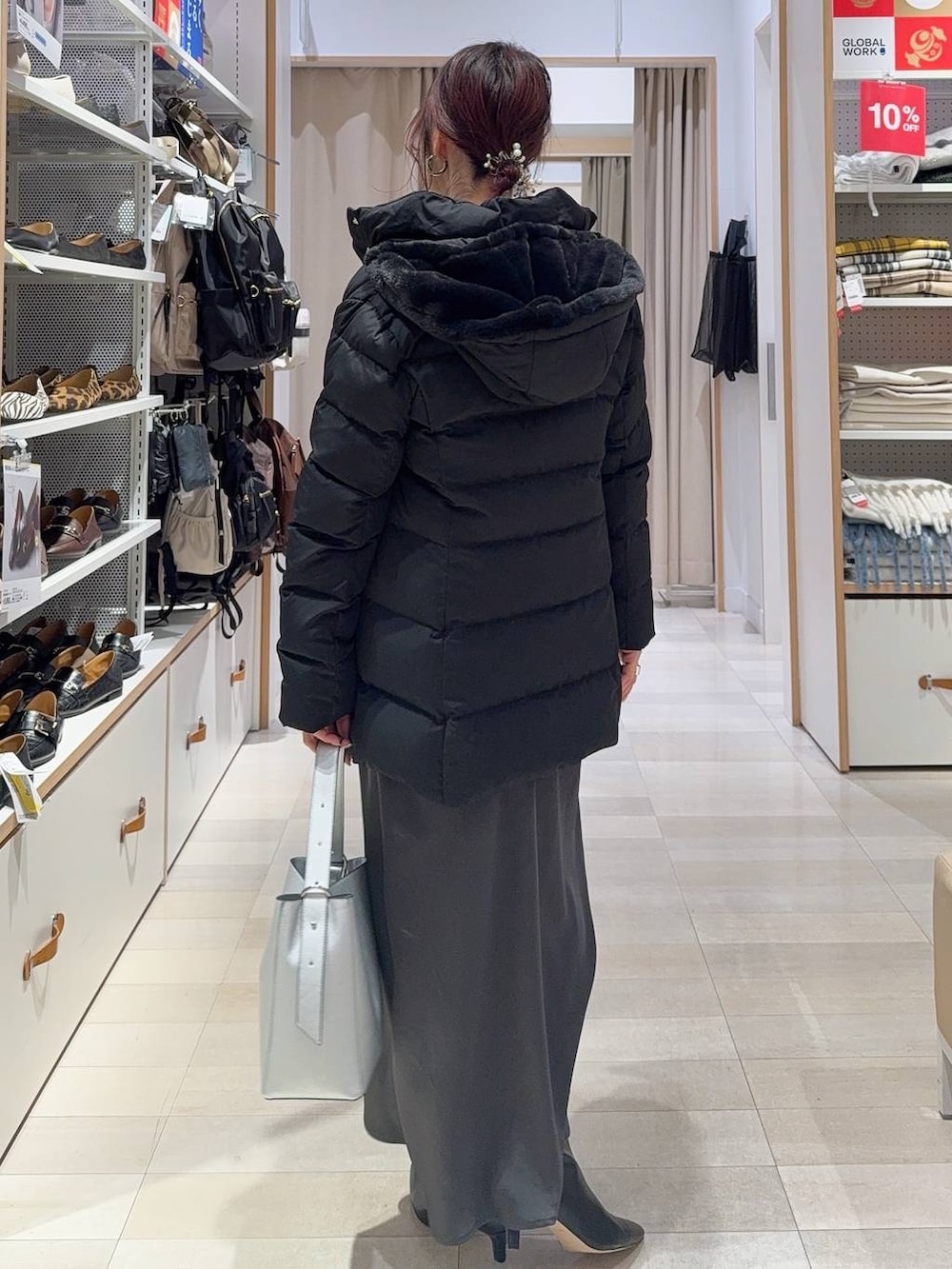 シルバー系のショルダーバッグ、ベージュ系のダウンジャケット/コート、グレー系のニット/セーターを着用したレディースの冬コーディネートの7枚目の写真