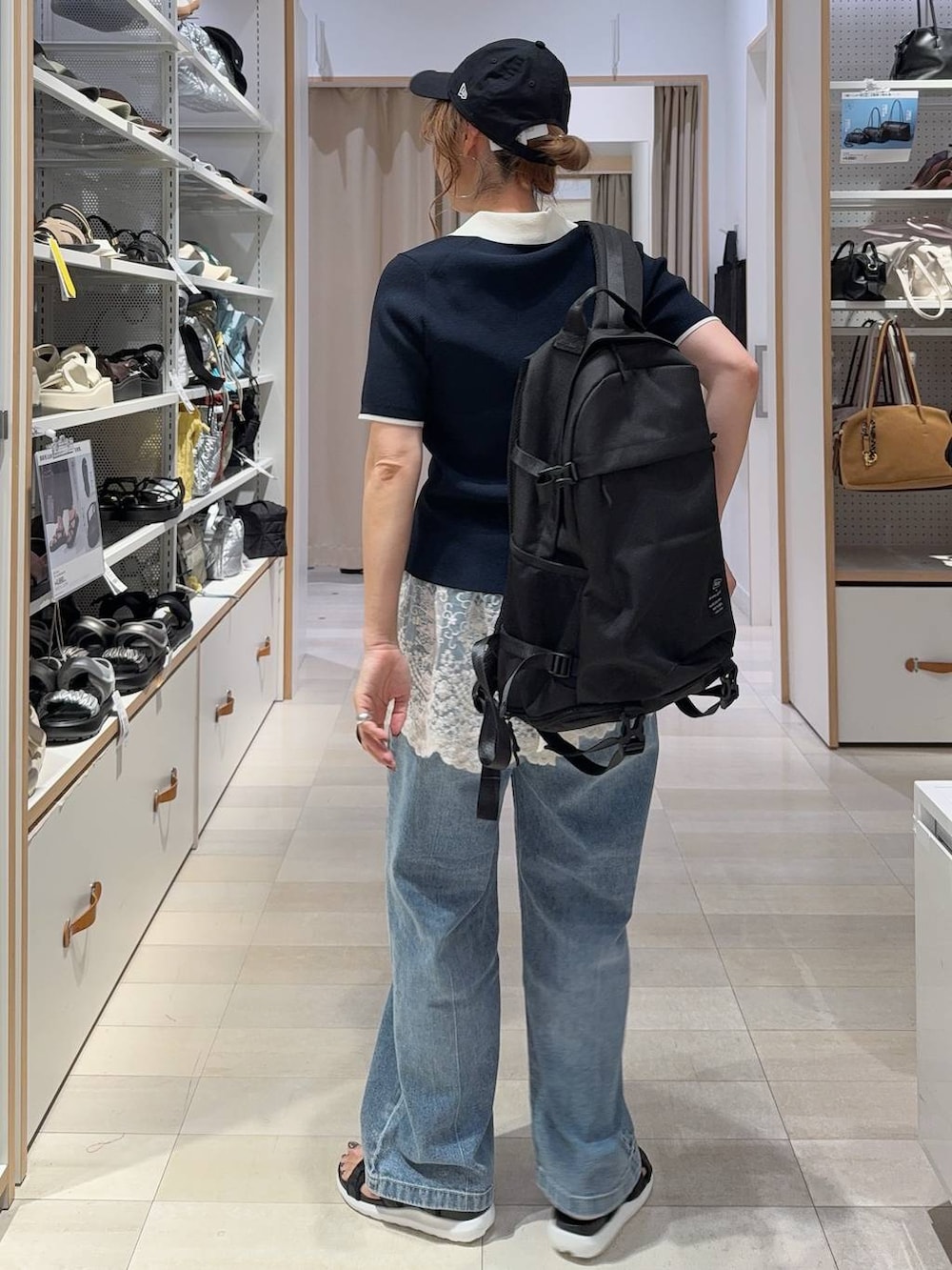 ブルー系のデニムパンツ、ブラック系のサンダル、ブルー系のニット/セーターを着用したレディースの夏コーディネートの4枚目の写真