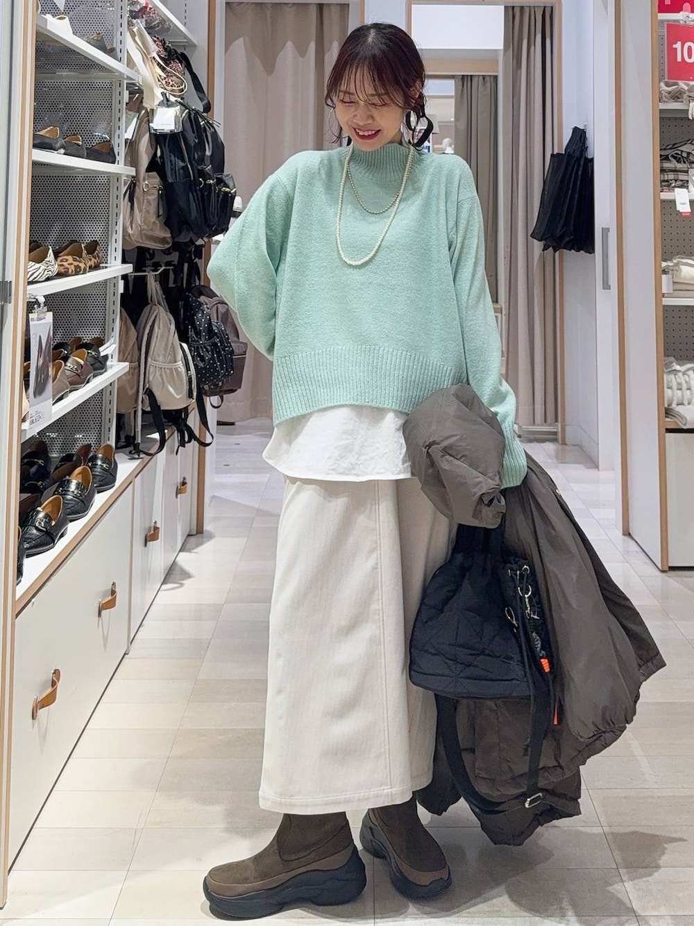 ブラウン系のダウンジャケット/コート、グレー系のスカート、ブラック系のハンドバッグを着用したレディースの冬コーディネートの2枚目の写真