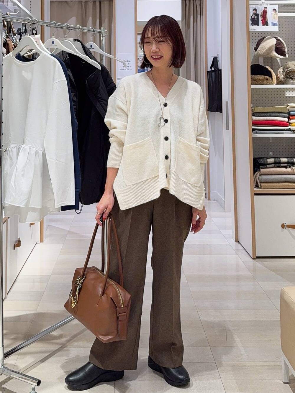 ブラウン系のボストンバッグ、ホワイト系のカーディガン/ボレロ、グレー系のスカートを着用したレディースの秋コーディネートの4枚目の写真