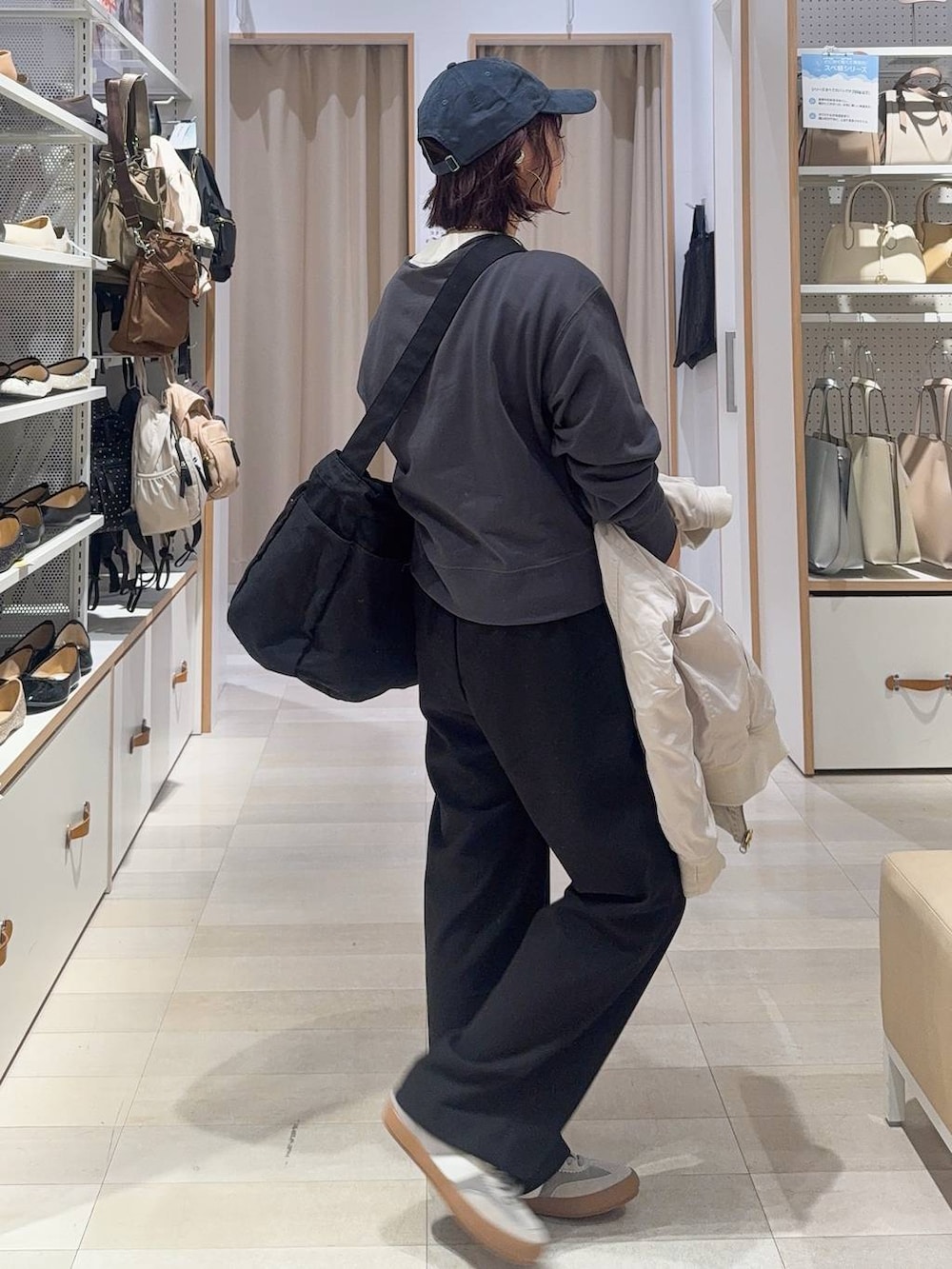 グレー系のスニーカー、ブラック系のショルダーバッグ、ベージュ系のブルゾンを着用したレディースの秋コーディネートの5枚目の写真